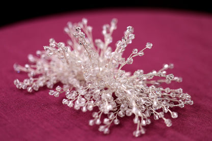 a close up of a small crystal snowflake on a pink surface