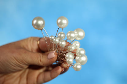 A hand holding a cluster of small white pearls against a blue background.