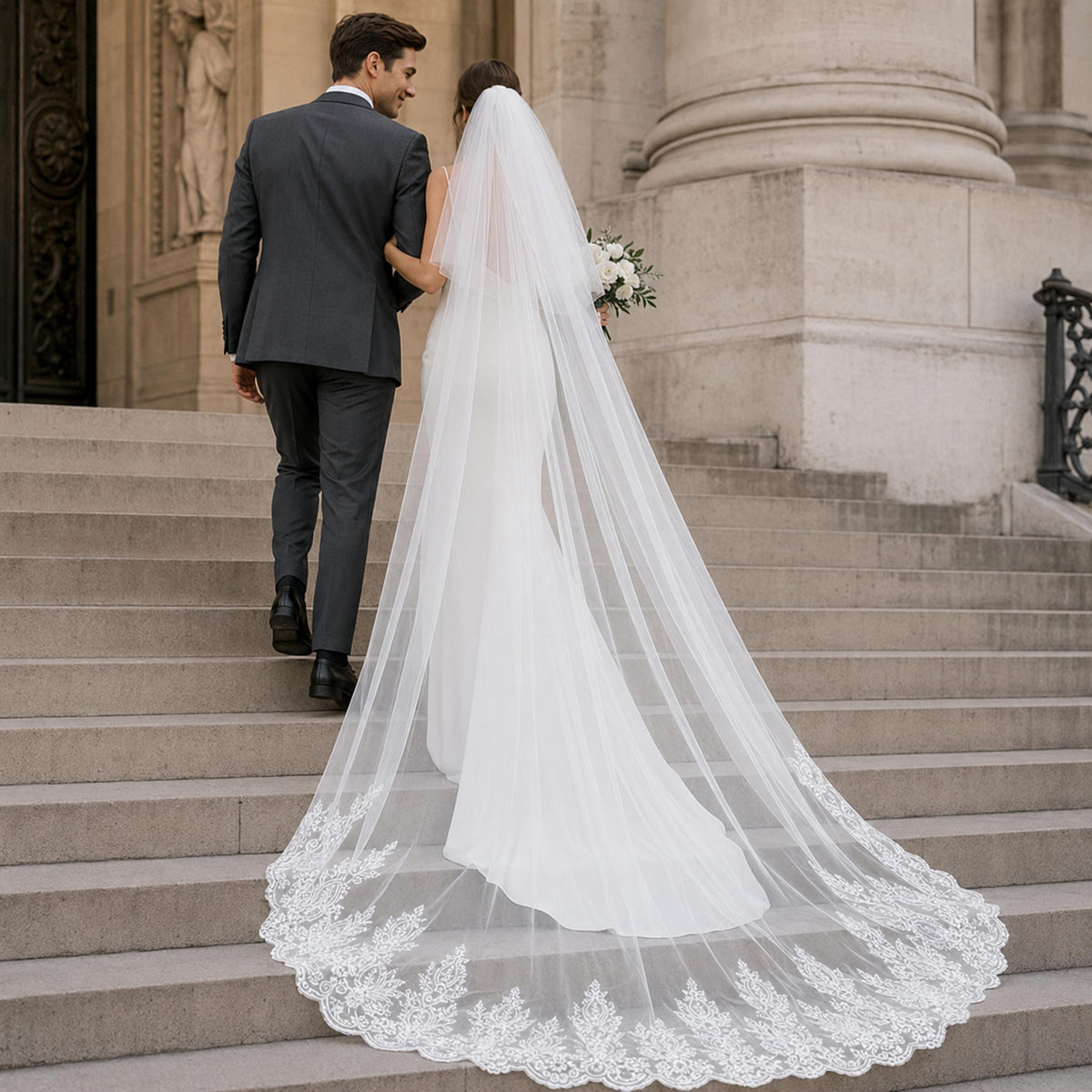 A bride and groom are walking down a set of stairs, with the bride wearing a long white wedding dress and veil, and the groom wearing a dark suit.