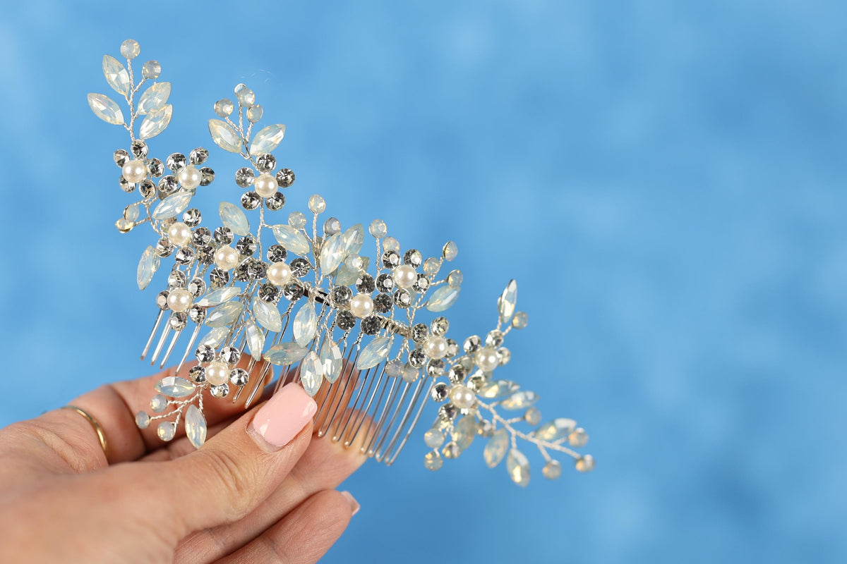 A hand holding a decorative hair accessory with a blue background.