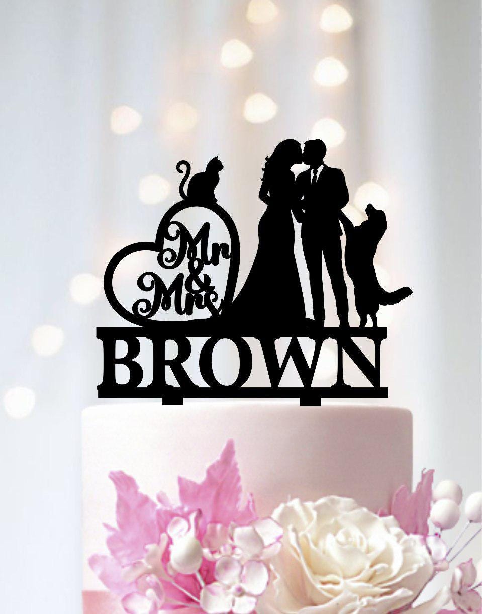 A black silhouette of a bride and groom kissing on a cake topper with the name "BROWN" below it.