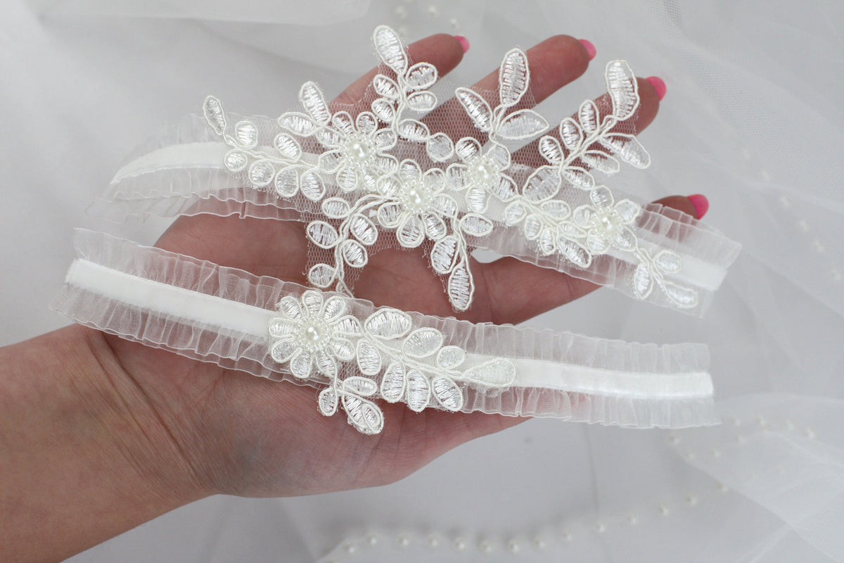 a hand is holding three wedding garters