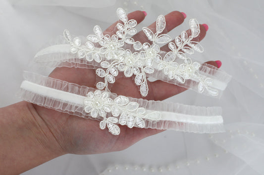a hand is holding three wedding garters